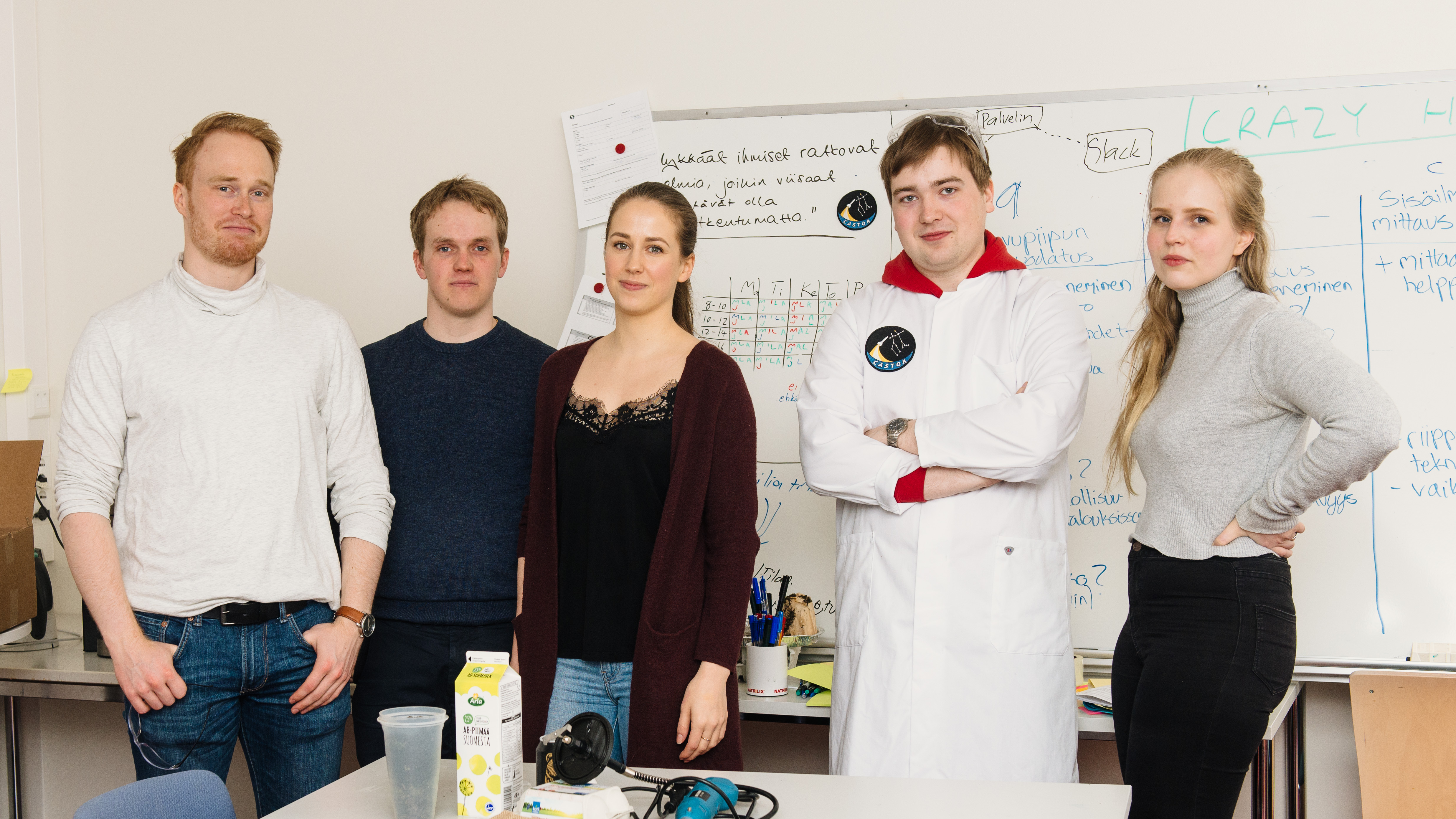 A group of five students standing in front of a classroom. 