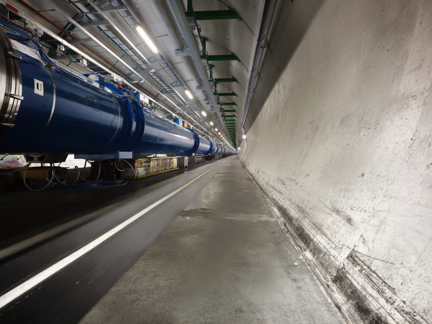 View of a concrete tunnel in which there is a series of blue and silver tubes