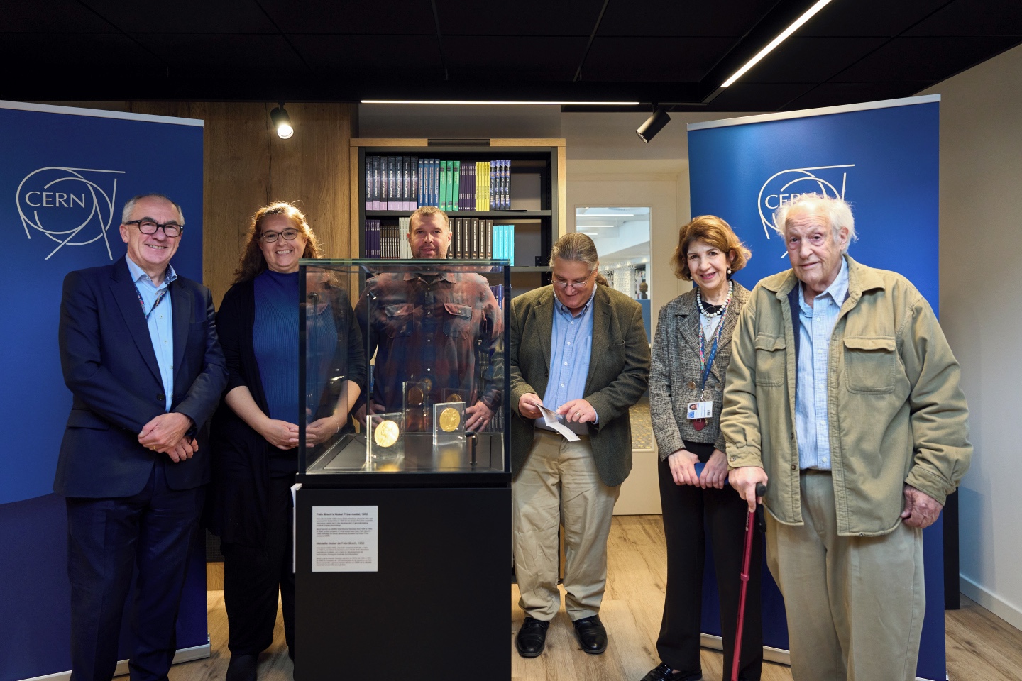 Group photo around a display case with two medals