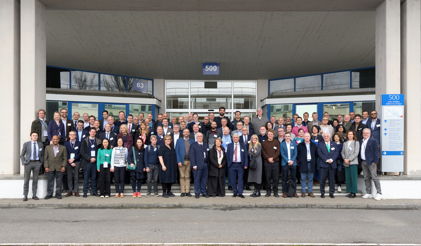 A large group of people stood at the entrance to a white building in three rows.