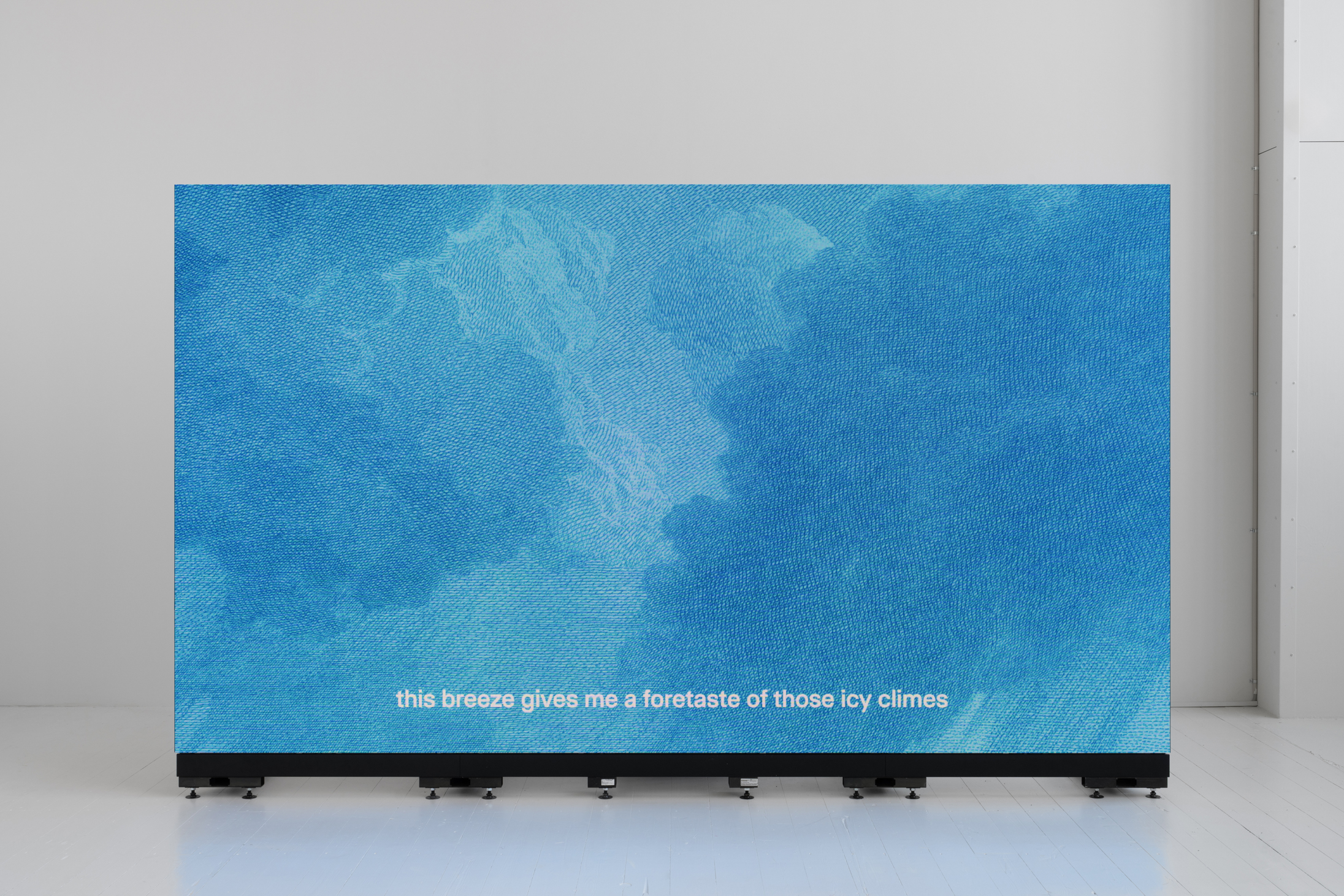 A big blue screen in front of a white background. The subtitles say "this breeze gives me a foretaste of those icy climes"