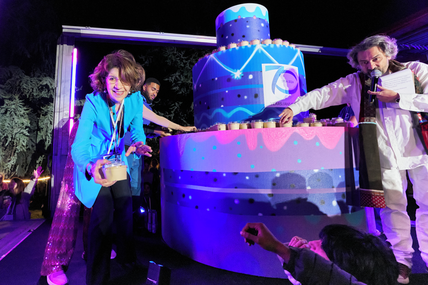 Two people standing next to a giant cake